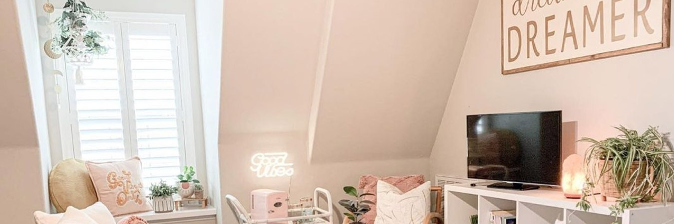 Dormer window with white Polywood shutters in a small and pink-styled attic room.